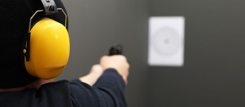 security guard training at a gun range wearing yellow earmuffs
